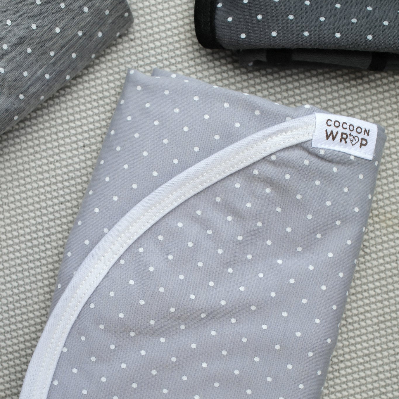 Gray wrap with white polka dots and 'Cocoon Wrap' label on a textured surface