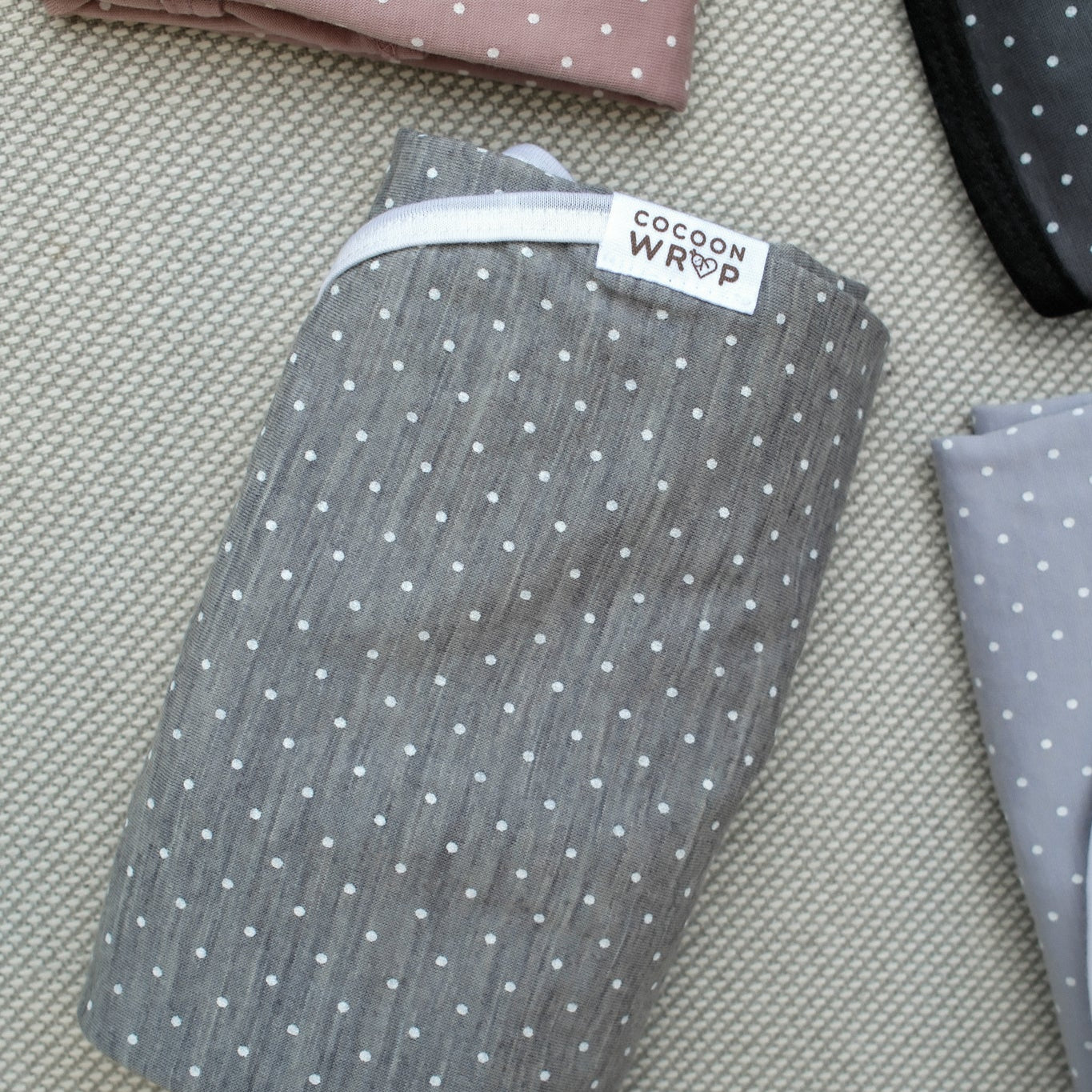 Folded fabric with a polka dot pattern on a textured surface, featuring a visible brand label.